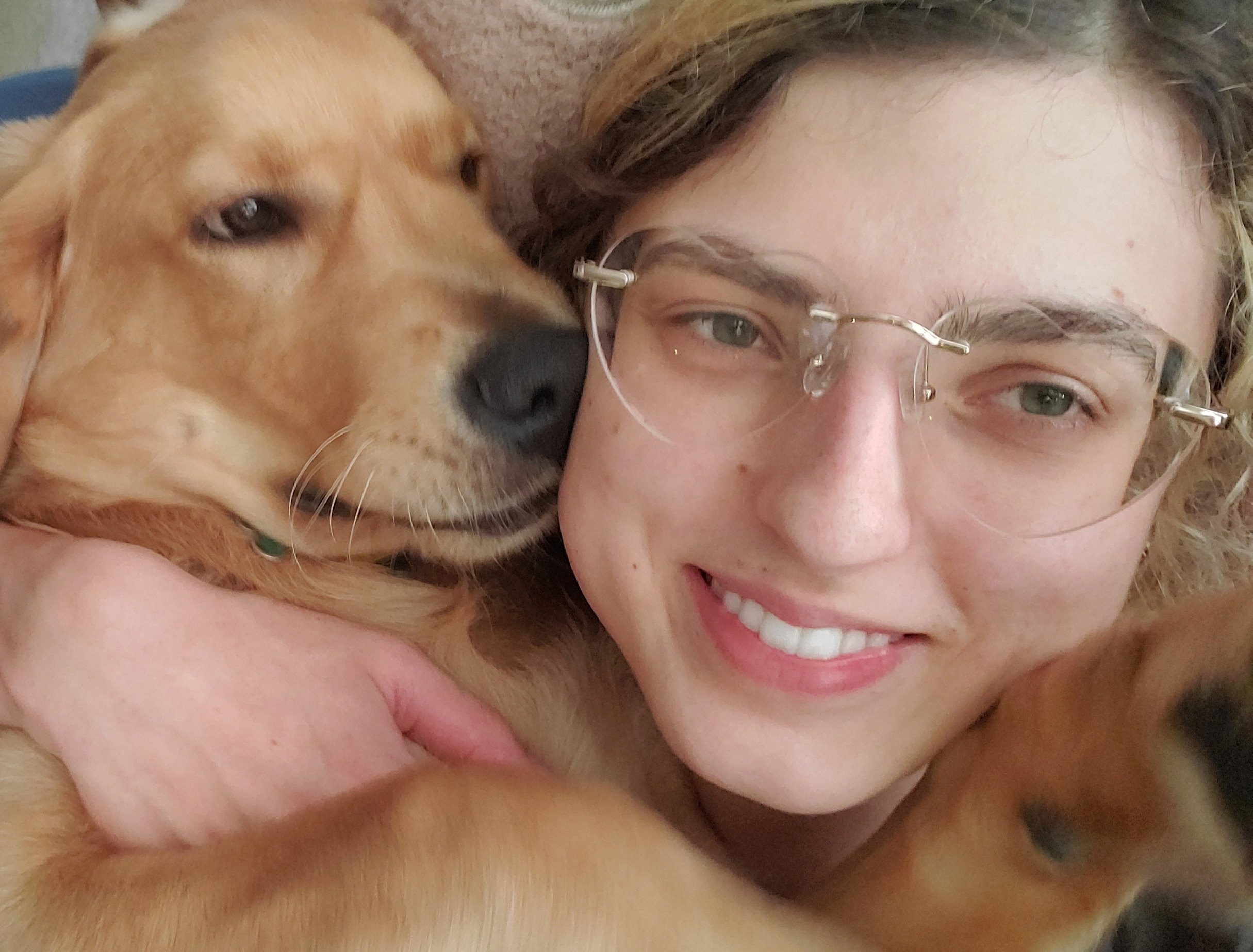 Young woman wearing glasses holding golden retriever dog